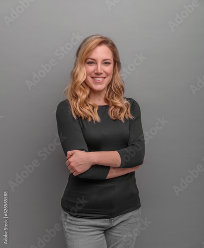 Smiling girl on a grey background, crossed her arms over her chest.
