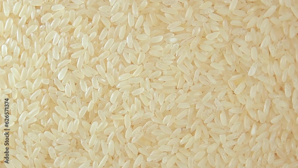 Dry Uncooked Parboiled Rice Background Slowly Rotating Left - Top View. Scattered Raw Long Grain Rice. Asian Cuisine and Culture. Healthy Eating Ingredients. Diet Food Dry Uncooked Parboiled Rice Background Slowly Rotating Left - Top View. Scattered Raw Long Grain Rice. Asian Cuisine and Culture. Healthy Eating Ingredients. Diet Food