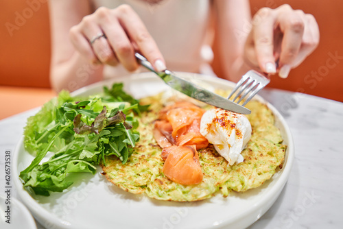 Wallpaper Mural Woman cuts Zucchini pancakes, with avocado, cheese cream, salmon and egg . Healthy breakfast, protein. Restaurant dish. Breakfast in cafe on a sunny morning, on the summer veranda Torontodigital.ca