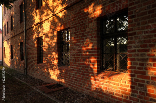 Okna w ceglanej ścianie oświetlone późnym słońcem.
