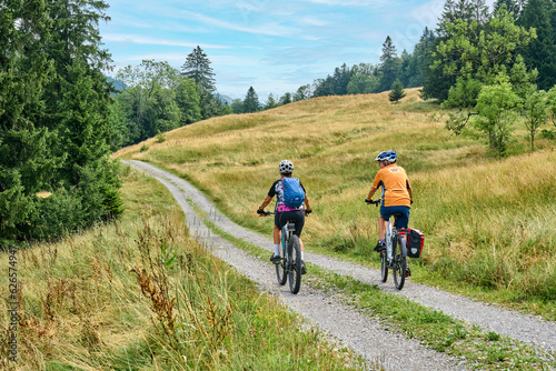 Fototapeta Naklejka Na Ścianę i Meble -  two senior girlfriends having fun during a cycling tour in the Allgau Alps near Oberstaufen, Bavaria, Germany