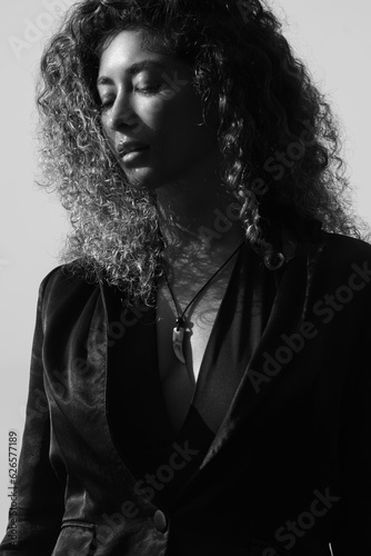 Beautiful girl with curly hair in a black jacket posing on the street, black and white photography