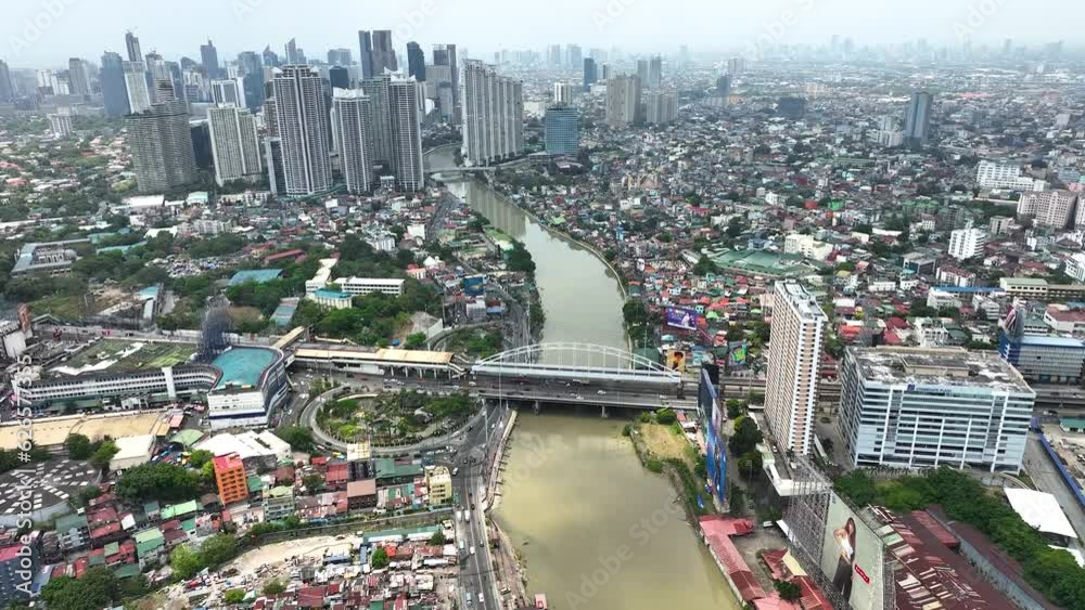 Manila cityscape at river banks aerial. Downtown area with cottages, skyscrapers, buildings. Urban Philippines city scape with streets and roads. Town drone shot. Poor Homes Along Rich Skyscrapers.