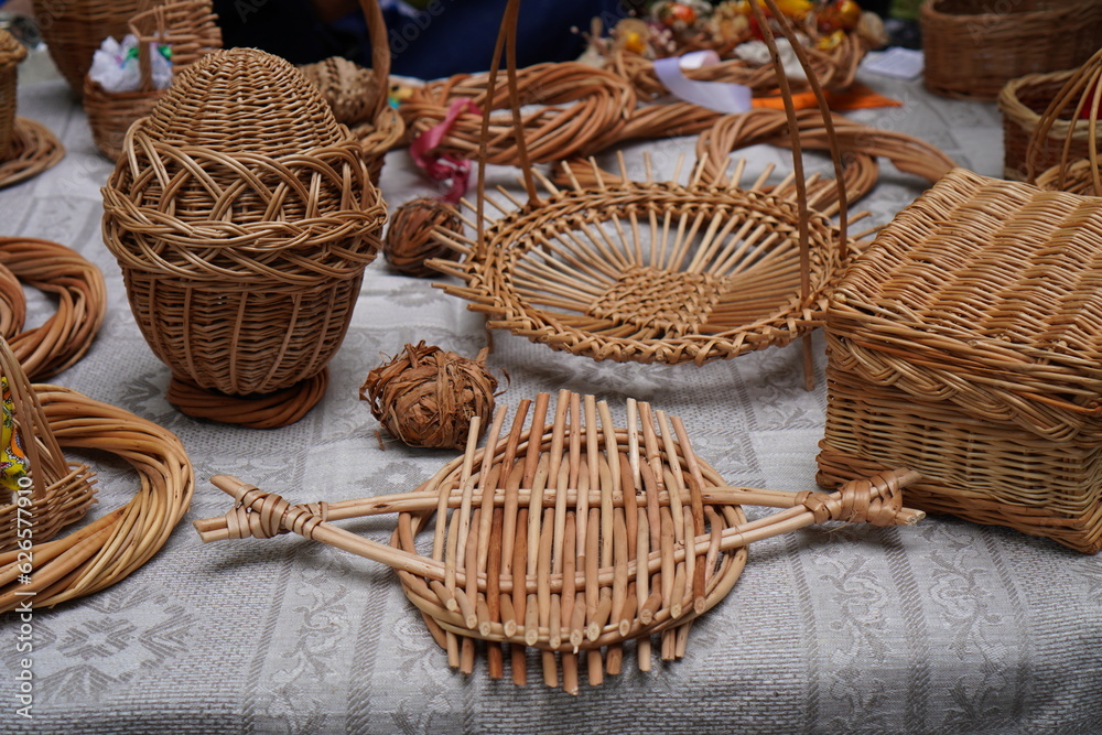 wicker products made of natural vines in the form of baskets, eggs, boxes, coasters, wreaths, on the table close-up. The concept of making interior items from natural materials