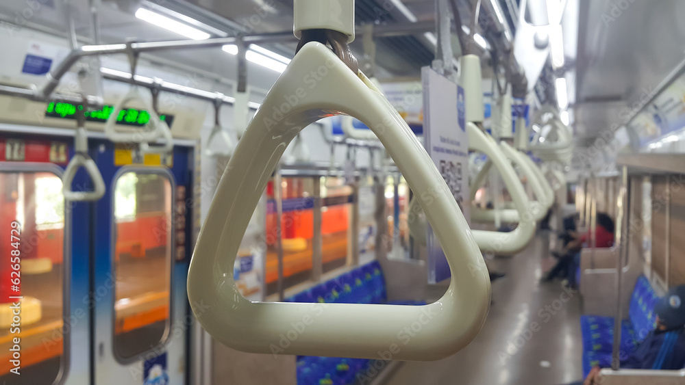 View of handles on ceiling rails for standing passenger. Handle on the commuter line train, prevent toppling. View inside the commuter line train carriage. View of handles on ceiling rails for standing passenger. Handle on the commuter line train, prevent toppling. View inside the commuter line train carriage.