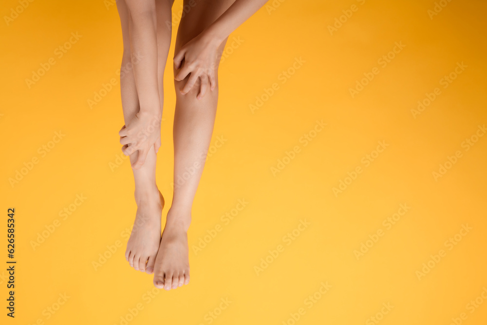 Explore legs healthcare with a close up of woman's legs, hands holding her pained legs on a vibrant yellow background. Concept of leg pain relief. Explore legs healthcare with a close up of woman's legs, hands holding her pained legs on a vibrant yellow background. Concept of leg pain relief.