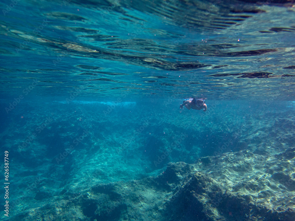 Vista subacquea di una donna che fa snorkeling nel mare del Plemmirio