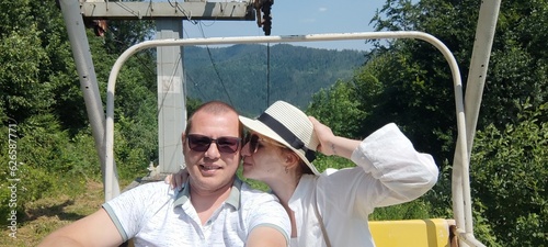 young couple on vacation on a cable car in the mountains in summer wearing sunglasses