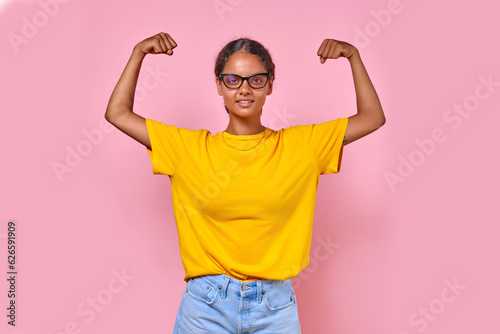 Slika na platnu Young happy strong Indian woman in strongman pose shows muscles on arms to demon