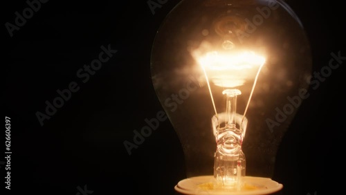 Close shot of a glowing tungsten lightbulb filament seen against a black background.