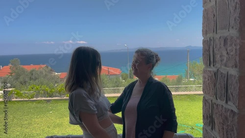 Senior old woman and her daughter is loving theirselves. Hugging, kissing, family concept in summertime, vacation. Sea and grass landscape, happy family. photo