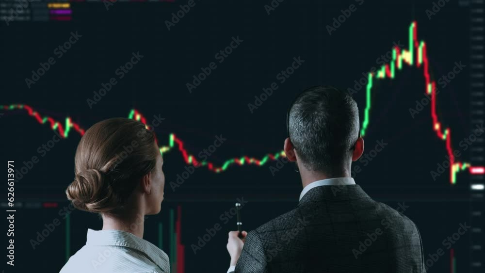 Colleagues traders are working with multiple computer screens full of charts and data analysis and stock broker trading online. Back view. Concept of bitcoin and stock market trading.