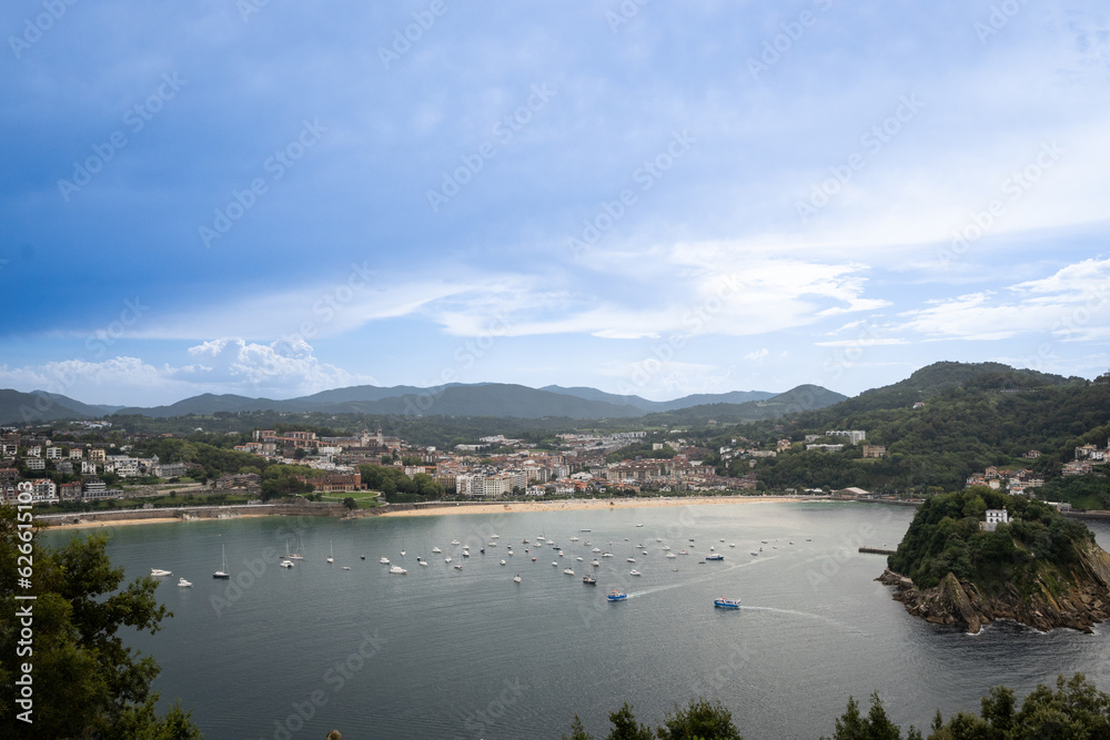 Fototapeta premium boats in the sea in the bahia de la concha Donosita-San Sebastian Spain on sunny summer day. Rocky island Isla de Santa Clara rises from the water of the Bay of Biscay
