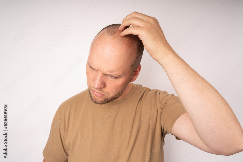 Obraz premium Young man in a brown t-shirt scratching his head and thinking about a better solution