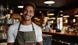 Smiling male barista holding digital tablet while standing in cafe.