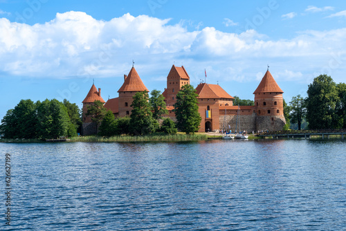 Trakai Castle in the middle of the lake, on a sunny summer day with some clouds.