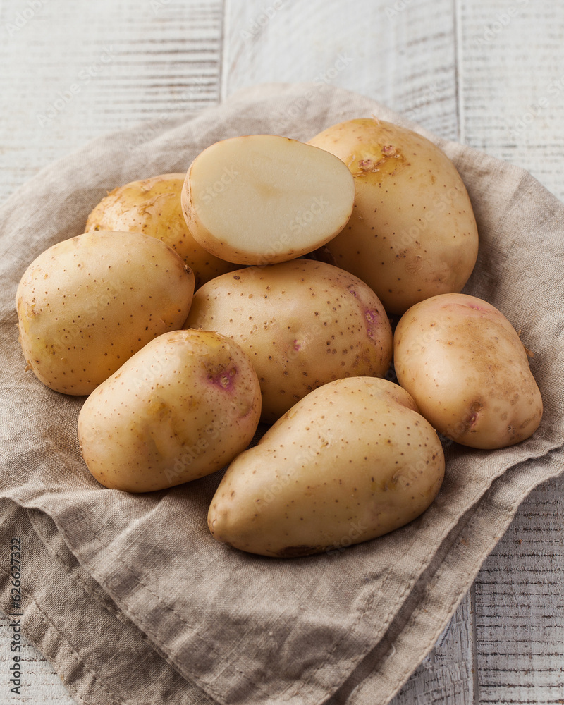 Washed potatoes whole and half on a napkin on a wooden table. Vegetables, root crops. Harvesting. Washed potatoes whole and half on a napkin on a wooden table. Vegetables, root crops. Harvesting.