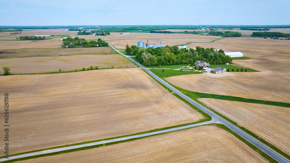 Aerial professionally mowed green lawn house property near farmland with empty, plowed fields