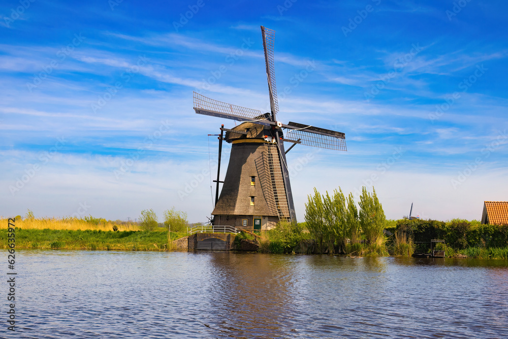 View from the canal, the shore showing one of the huge mills with the outlet of the mouth of the water to the canal. Kinderdijk, Netherlands.