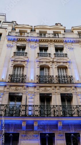 Belle façade d'un batiement parisien de luxe ou hotel chic, sous un beau jour, avec de jolis projecteurs bleus, beauté urbaine, immeuble en ancien pierre, style riche, à plusieurs étages, balcon photo