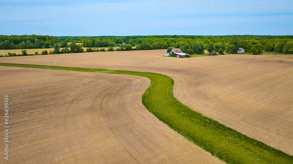 Flat farmland terrain with snaking river of green grass aerial