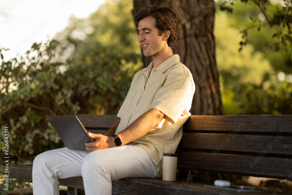 Happy millennial man freelancer working at public park Happy millennial man freelancer working at public park