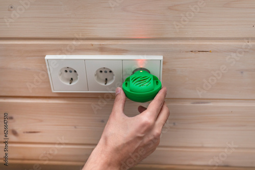 Close-up of hand holding fumigator near socket. Useful device against insects photo