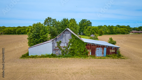 Aerial dirt farmland with old barn with ivy growing on it