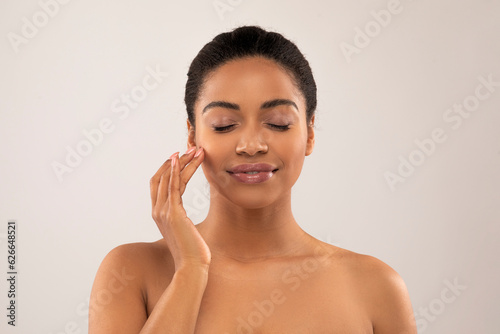 Sensual attractive topless young black woman enjoying smooth facial skin