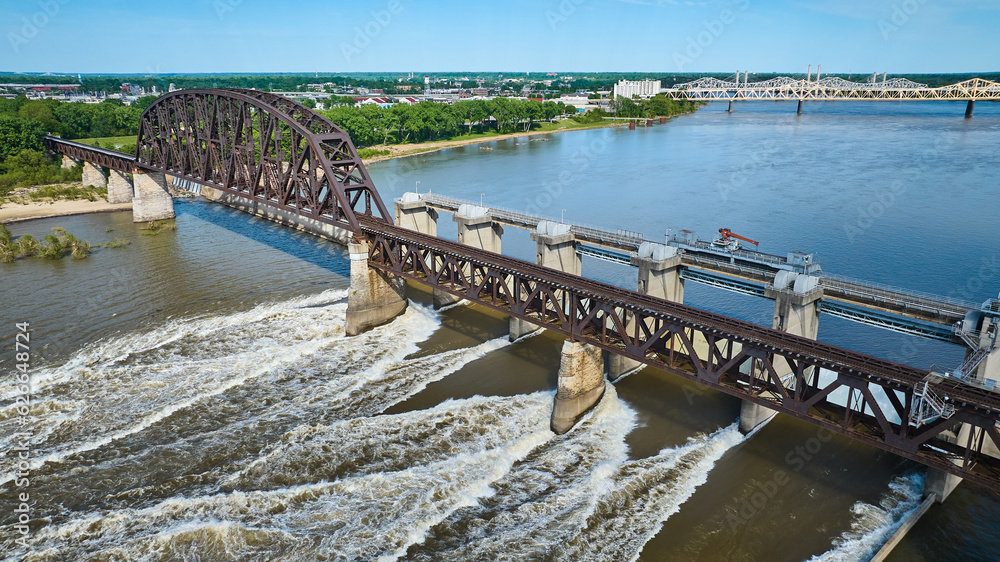 Truss arch bridge over large dam blue river water and white water rapids aerial of distant shore