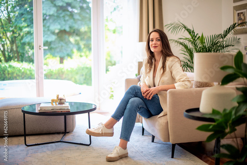 фотографія Attractive brown-haired woman is sitting in an armchair at home while looking at