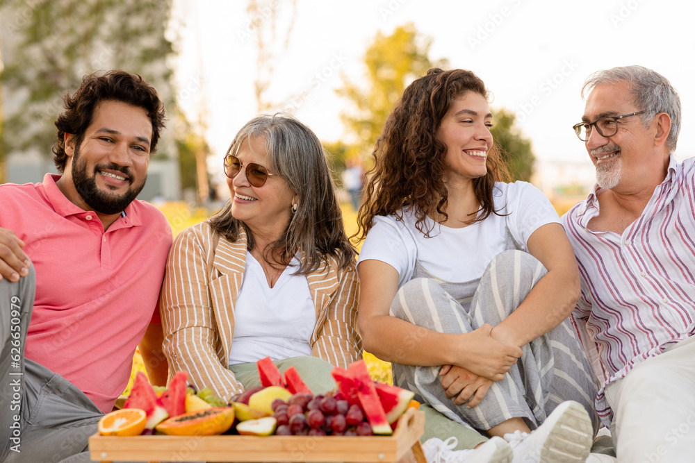 Positive european senior and adult people enjoy picnic, fruits, food in park, outdoor, close up Positive european senior and adult people enjoy picnic, fruits, food in park, outdoor, close up