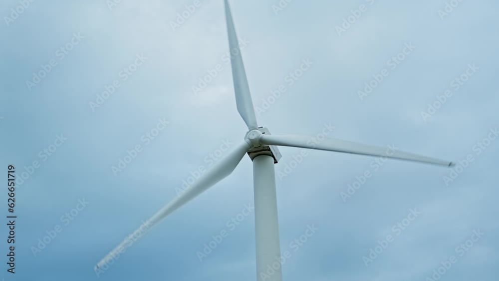 Windmill. Wind power turbine generating clean renewable energy. Central composition. Clouds at background. Green energy concept. 4K, UHD Windmill. Wind power turbine generating clean renewable energy. Central composition. Clouds at background. Green energy concept. 4K, UHD