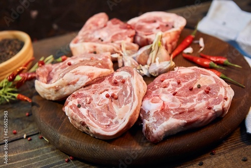 Pieces of raw meat, hot pepper and garlic lie on a wooden cutting board. Raw food for cooking.