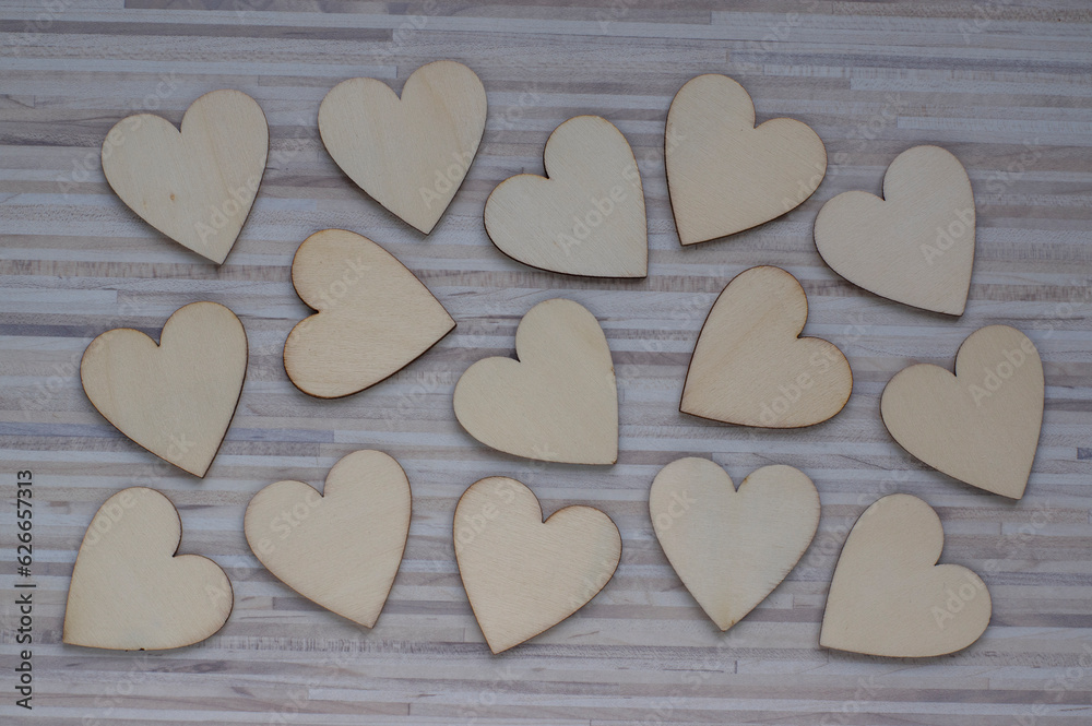 Love Valentines day background, group of light wooden hearts spread on gray striped table, flat lay Love Valentines day background, group of light wooden hearts spread on gray striped table, flat lay
