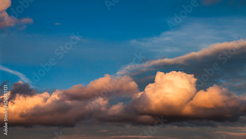 Panorama of sunset blue sky with orange fluffy clouds, atmospheric backdrop. Panoramic view of cloudscape, amazing sky background, cozy wallpaper. Design style backgrounds concept. Copy ad text space