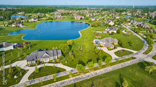 Textured techno road through rich expensive neighborhood property fresh cut grass homes near pond