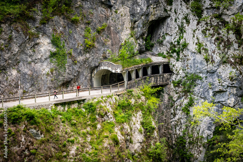 Narrow mountain road with tunnels carved through the massive rocky cliffs of slovenain Alps, above Soca river canyon