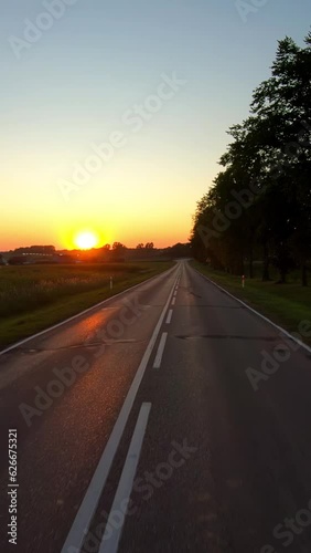 On a rural road to sunset, vertical pov