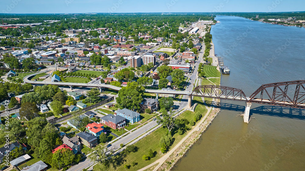 Aerial iron arch bridge over long Ohio River water with city town houses and highway