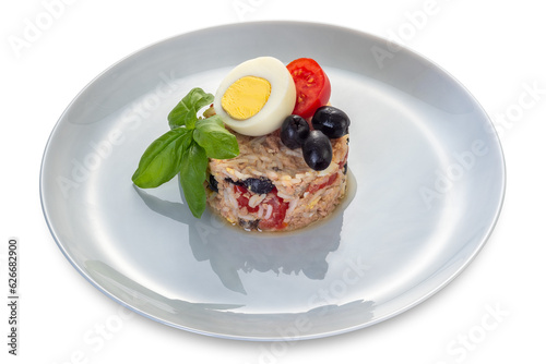 Rice salad with tuna, tomatoes, olives and boiled egg and basil leaves in pearl-coloured plate isolated
