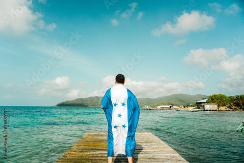 A person with honduras flag in front a sea and a island,