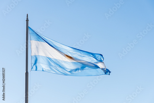 Argentine flag on a mast fluttering in the sky.