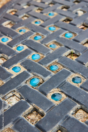Tilted view of black brick path with every other pattern of varying and missing blue marble stones
