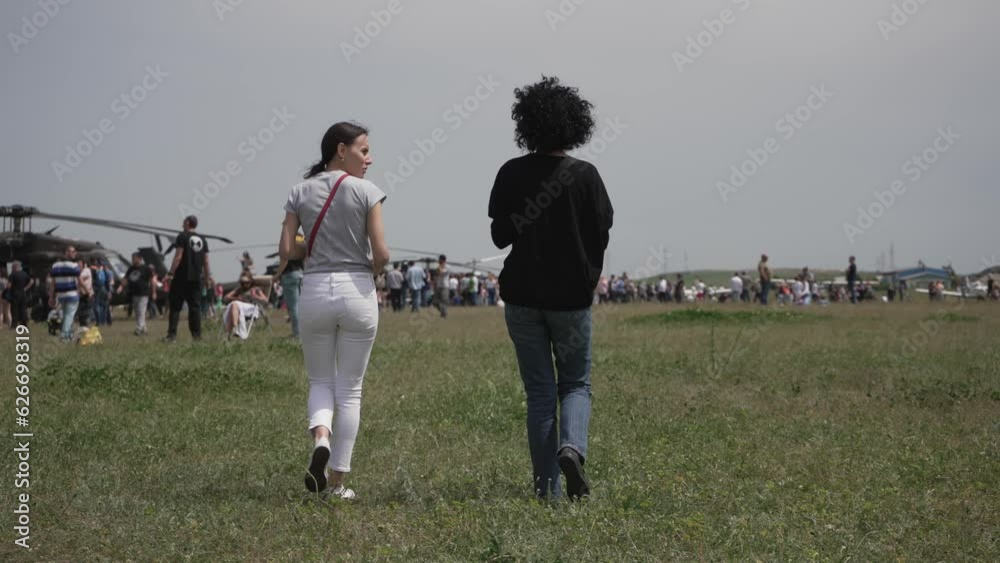 Two woman visitors on airshow display with military hellicopters and planes Two woman visitors on airshow display with military hellicopters and planes