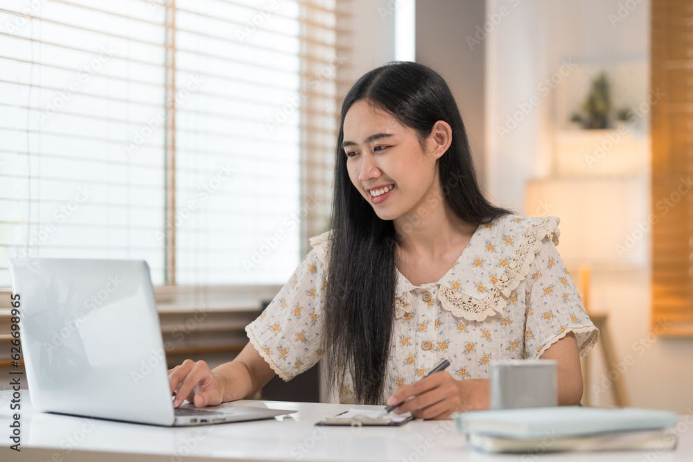 Beautiful young woman using laptop and making notes on notebook. Beautiful young woman using laptop and making notes on notebook.