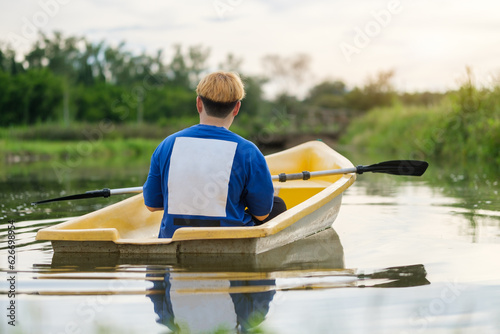 Rear view of male tourists rowing boat with oars in river. Travel, vacation holiday and outdoor activity. photo