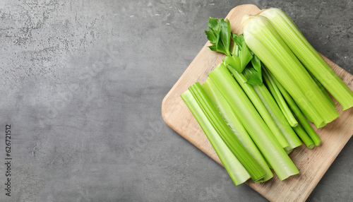 Board with fresh green cut celery on grey table  top view. Space for text