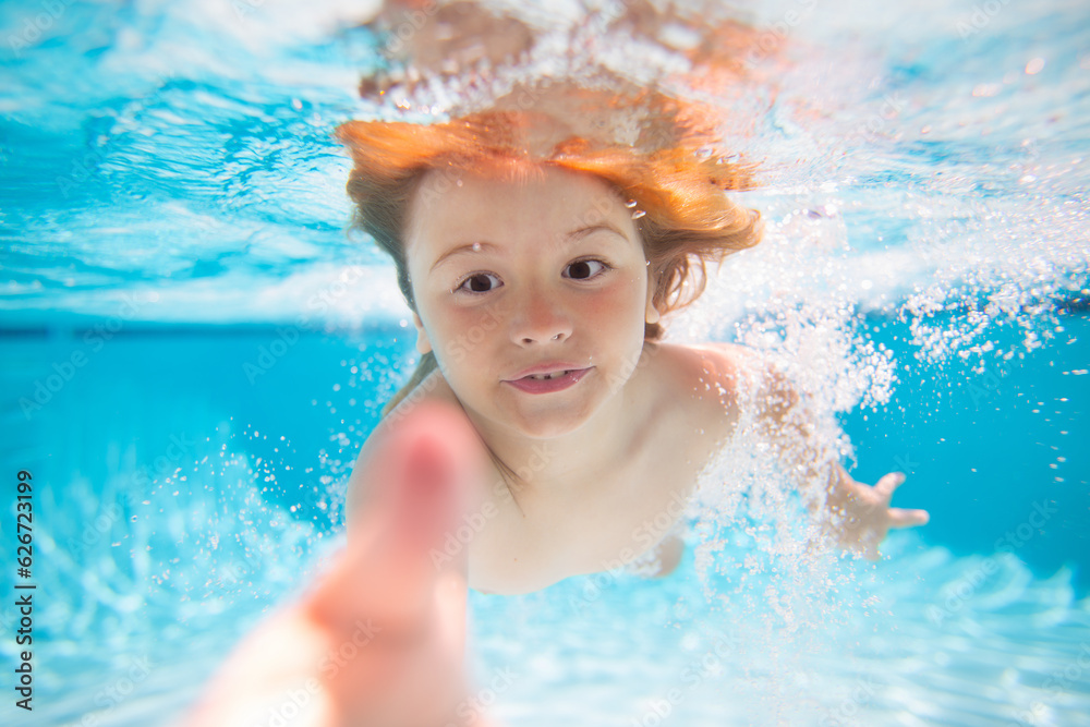 Summer kids in water in pool underwater. Funny kids face underwater. Underwater child swims in pool, healthy child swimming and having fun under water.