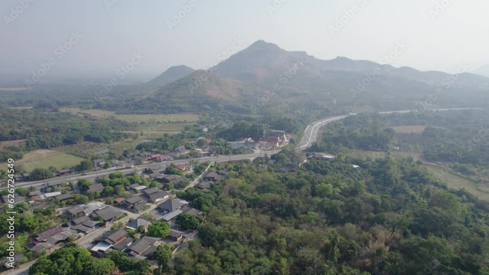 Zoom out of a morning village surrounded by forests at the bottom of green mountains Thailand. Zoom out of a morning village surrounded by forests at the bottom of green mountains Thailand.